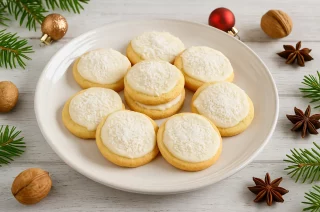 Helle Kokostaler, bestrichen mit weißer Schokolade und bestreut mit Kokosflocken, serviert auf weihnachtlichem Teller