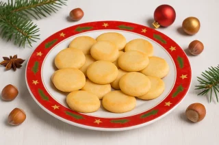 Marzipan-Plätzchen auf einem weihnachtlich dekorierten Teller mit Tannenzweigen und Kugeln