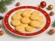 Marzipan-Plätzchen auf einem weihnachtlich dekorierten Teller mit Tannenzweigen und Kugeln