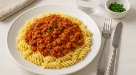 Tomatenpasta mit Hackfleisch und cremiger Tomatensauce, serviert auf einem Teller mit Nudeln