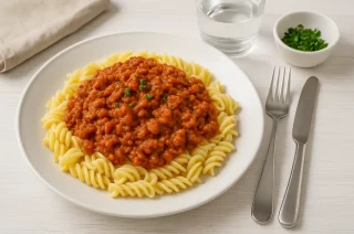Tomatenpasta mit Hackfleisch und cremiger Tomatensauce, serviert auf einem Teller mit Nudeln