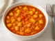 Kartoffel-Reis-Eintopf mit Kartoffelstücken, Reis und Tomaten in Schüssel auf Holztisch
