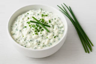 Cremiger Gemüse-Dip mit Quark, Hüttenkäse und Kräutern in einer weißen Schale, serviert