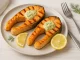 Gegrillte Lachssteaks mit Dill-Knoblauch-Butter und Zitronenscheiben auf Teller angerichtet