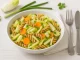 Schale mit Nudelsalat aus Chicorée, Möhren und Frühlingszwiebeln auf weißem Holzhintergrund