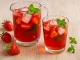 Apfelweinbowle mit frischen Erdbeeren, Minze und Eiswürfeln in einem Glas auf Holztisch