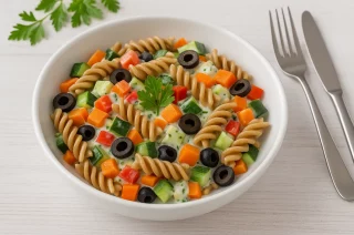 Bunter Nudelsalat mit Vollkornnudeln, Paprika, Karotten, Oliven und cremigem Lupinenjoghurt in Schüssel