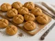 Frisch gebackene Kümmelbrötchen auf weißem Holztisch, bestäubt mit Mehl und Kümmel, daneben Tuch und Messer