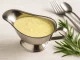 Cremige Senf-Estragon-Sauce in einer Edelstahlsauciere, serviert mit Estragon auf Holztisch