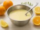 Frisches Zitrusdressing mit Orange, Honig und Buttermilch in einer Edelstahlschüssel auf hellem Holzhintergrund