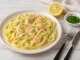 Bandnudeln mit cremiger Lachs-Sahne-Sauce und Kräutern auf weißem Teller serviert