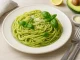 Pasta mit cremigem Avocado-Pesto, garniert mit Basilikum und Parmesan auf weißem Teller