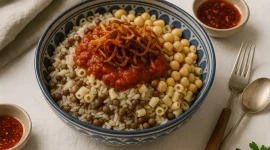 Bunte Schüssel Koshari mit Reis, Linsen, Nudeln, Tomatensoße und knusprigen Zwiebeln auf hellem Tisch