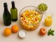 Glaskrug mit Silvesterbowle, frischen Früchten, Minze und Eiswürfeln auf festlichem Tisch mit Gläsern
