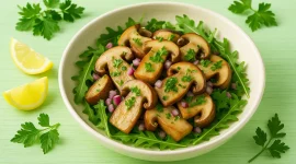 Steinpilzsalat mit frischen Kräutern und Zwiebeln auf hellgrünem Holztisch mit deutlicher Maserung, serviert in heller Schüssel
