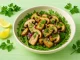 Steinpilzsalat mit frischen Kräutern und Zwiebeln auf hellgrünem Holztisch mit deutlicher Maserung, serviert in heller Schüssel